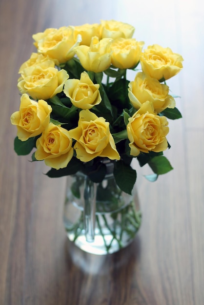 Photo un vase de roses jaunes avec des feuilles vertes sur une table