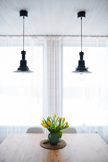 Vase Avec Tulipes Jaunes Sur Table En Bois Et Deux Lampes Suspendues Au-dessus De La Fenêtre Dans La Salle De Séjour