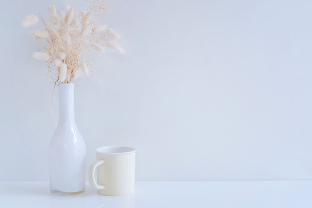 Vase en verre blanc maquette avec fleur de foin et mug jaune sur tableau blanc