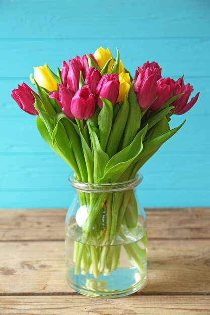 Vase en verre avec bouquet de belles tulipes sur fond de bois