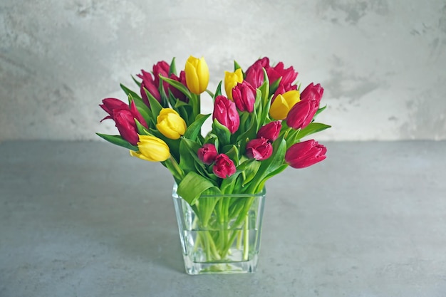 Vase en verre avec bouquet de belles tulipes sur fond de couleur