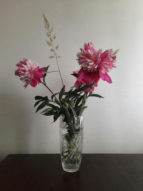 Vase en verre avec des fleurs sur la table en bois sombre