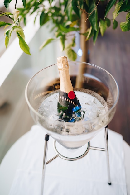 Vase en verre avec de la glace avec une bouteille de champagne