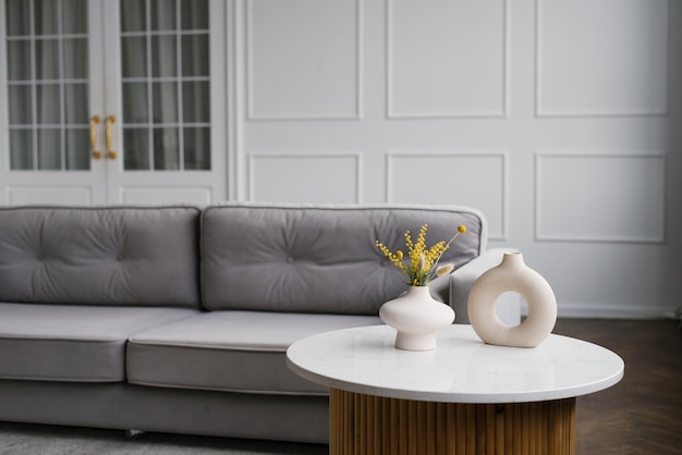 Vases élégants modernes sur la table basse près du canapé gris dans le salon de la maison