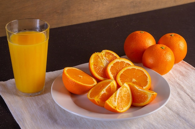 Vaso de cristal con zumo de naranja fresco y fruta fresca sobre una mesa