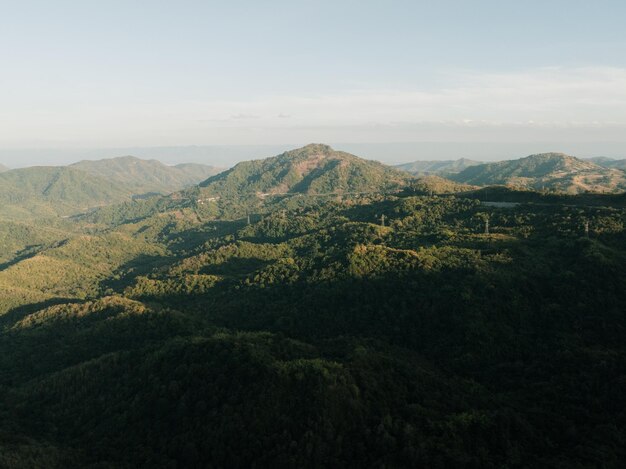 Une vaste chaîne de montagnes couverte d'épaisses forêts vertes sous la lumière douce du soleil de fin d'après-midi évoquant un sentiment de tranquillité