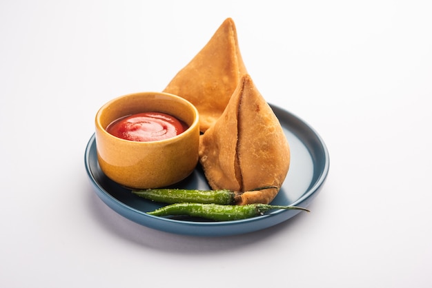 Veg Samosa - est une collation indienne croustillante et épicée en forme de triangle qui a une couche extérieure croustillante de maida et une garniture de purée de pommes de terre, de pois et d'épices