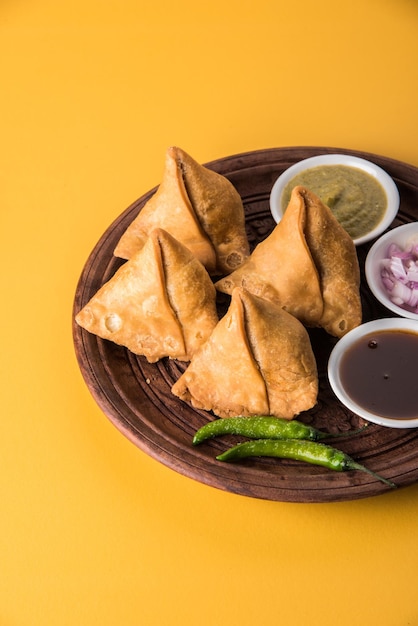 Veg Samosa - est une collation indienne croustillante et épicée à l'heure du thé servie avec du piment vert frit, de l'oignon et du chutney ou du ketchup