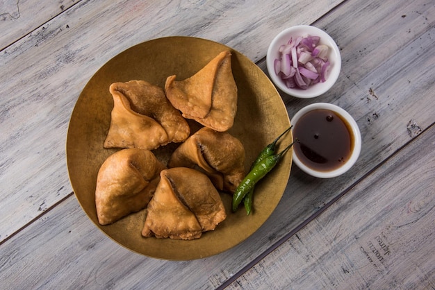 Veg Samosa - est une collation indienne croustillante et épicée à l'heure du thé servie avec du piment vert frit, de l'oignon et du chutney ou du ketchup