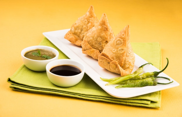 Veg Samosa est une collation populaire indienne ou de la malbouffe servie avec du piment vert frit, de l'oignon et du chutney ou du ketchup