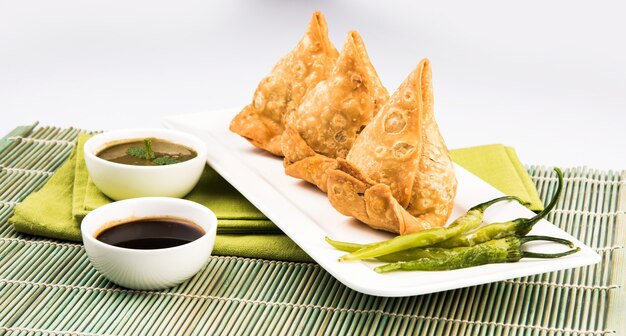 Veg Samosa est une collation populaire indienne ou de la malbouffe servie avec du piment vert frit, de l'oignon et du chutney ou du ketchup