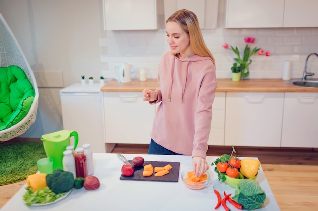 Vegan belle femme blonde cuisine des crudités dans la cuisine.