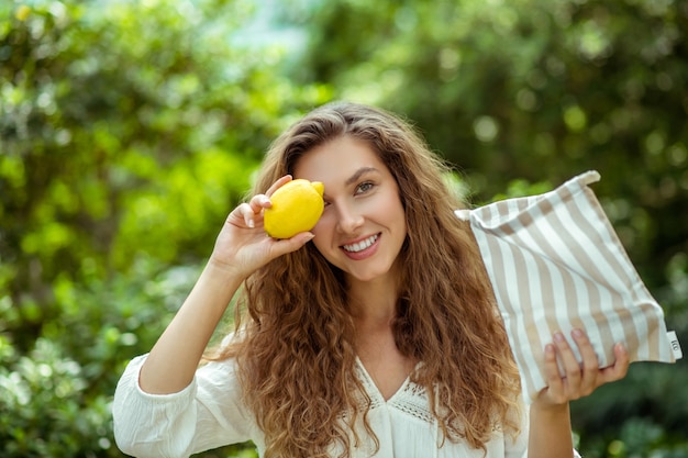 Vegan. Wowan mignon en chemise blanche tenant un citron et souriant