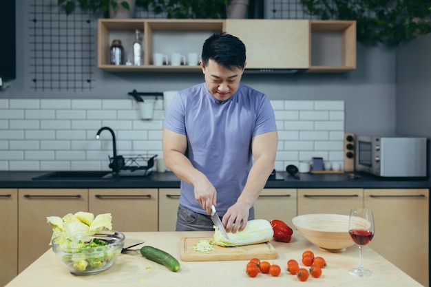 Un végétarien asiatique coupe des légumes à la maison Un asiatique prépare une salade pour le dîner