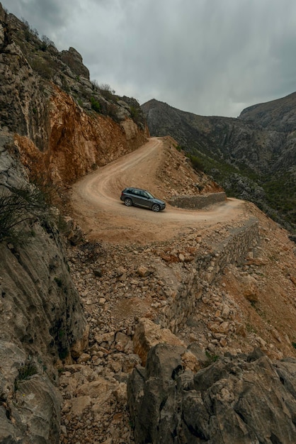 Photo véhicule 4x4 moderne descendant un chemin de terre escarpé à travers un col entre les montagnes