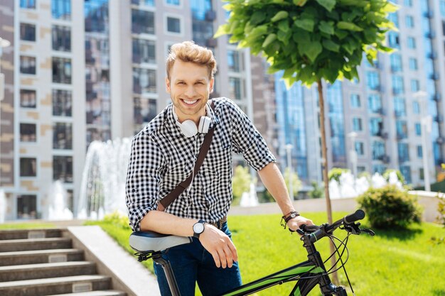 Véhicule écologique. Heureux Homme Agréable Appuyé Sur Son Vélo Tout En Vous Regardant