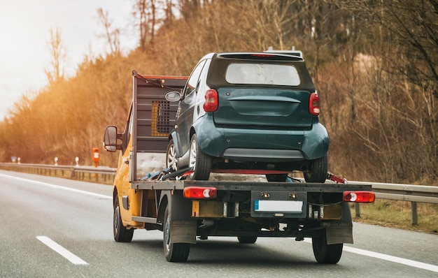 Photo véhicule de remorquage avec voiture en panne sur route de campagne vécile transportant une voiture sur l'autoroute concept de transport de service de voiture