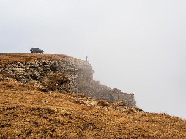 Véhicule tout-terrain au bord d'une falaise abrupte d'automne avec dense