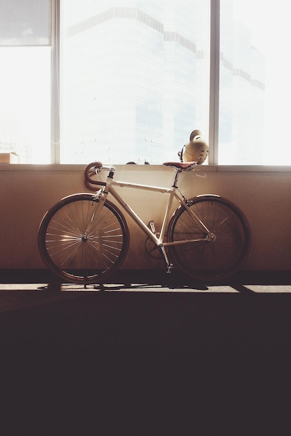 Photo un vélo appuyé sur le mur près de la fenêtre de la maison.