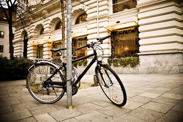 un vélo est attaché à un poteau sur le trottoir