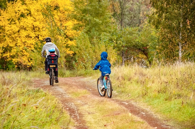 Vélo en famille dans le parc de l'automne doré, père et enfants actifs font du vélo, sport en famille et fitness en plein air