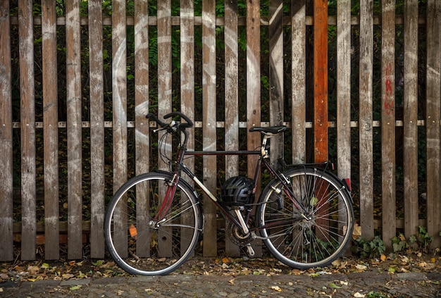 Vélo garé contre une clôture en bois et un casque de sécurité noir