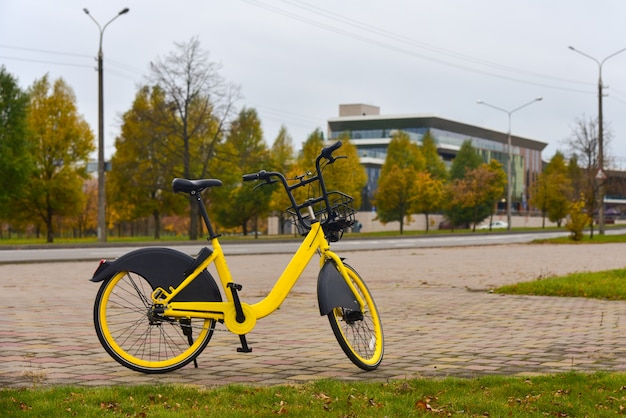 Vélo jaune pour le partage est debout près d'une route dans la ville