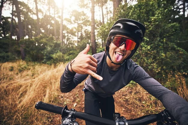 Vélo de montagne cyclisme et fitness avec un homme faisant un signe de la main shaka pendant l'entraînement ou l'exercice dans la nature brésilienne Portrait d'un athlète masculin professionnel faisant de l'éducation cardio dans une forêt