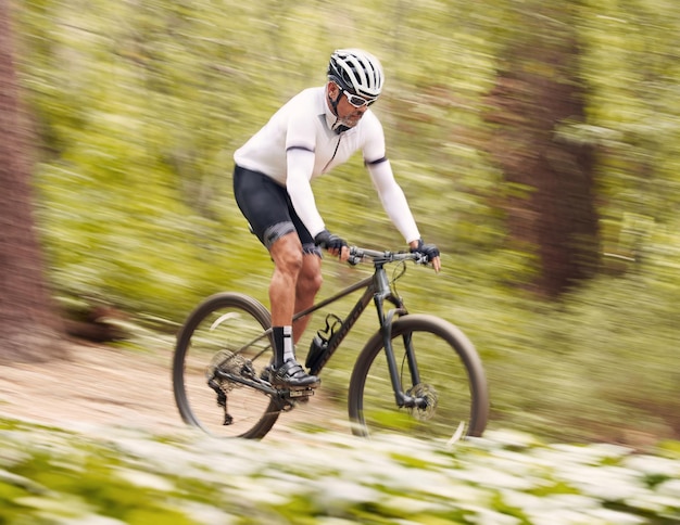 Photo vélo nature ou homme sportif rapide voyage et voyage sur une aventure hors route défi en plein air ou exercice de vélo flou de vitesse d'action de cyclisme ou entraînement d'athlète fitness et compétition dans les bois
