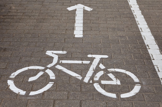 Vélo panneau routier sur piste cyclable peinte sur le trottoir.