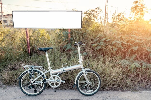 Vélo pliant garé sur le pré avec une affiche blanche qui brille