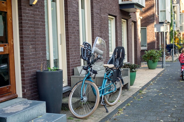 Un vélo de ville avec siège de sécurité pour enfant et verre de sécurité est garé dans la rue près des marches