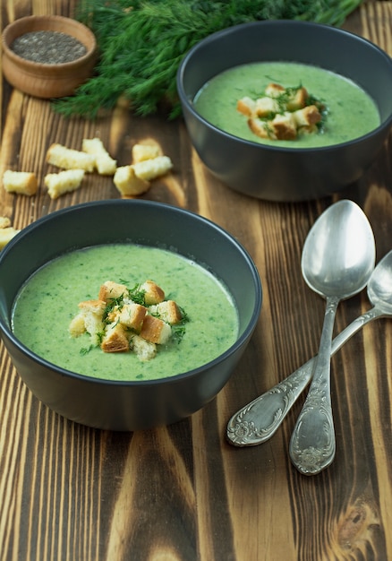 Velouté d'épinards avec craquelins, herbes et graines de chia. Soupe verte servie dans un bol sur une table en bois. . Lay plat.