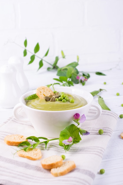 Velouté de petits pois aux croûtons dans un bol blanc