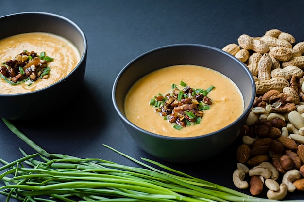 Velouté de potiron aux herbes et noix, servi dans un bol sombre.