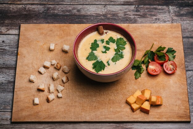 Velouté de potiron aux légumes dans une assiette sur une planche à découper avec du persil