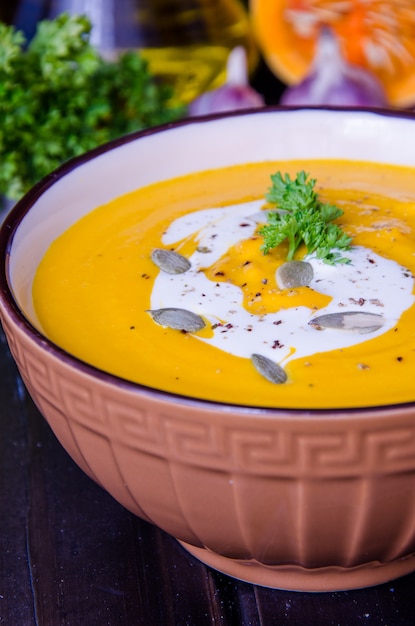 Velouté de potiron aux lentilles rouges et carottes dans un bol sur un fond en bois