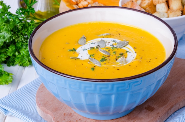 Velouté de potiron aux lentilles rouges et carottes dans un bol sur un fond en bois