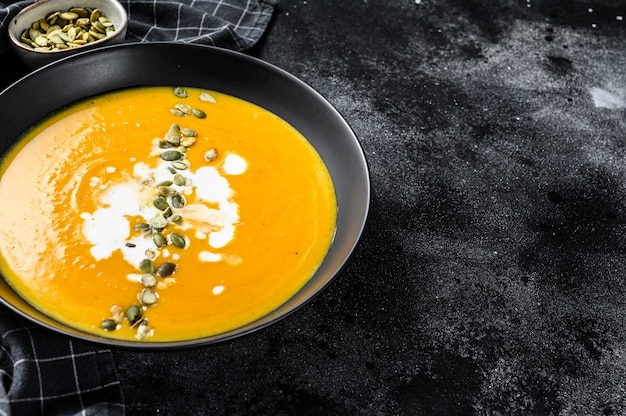 Velouté de potiron à la crème et graines de citrouille. fond noir