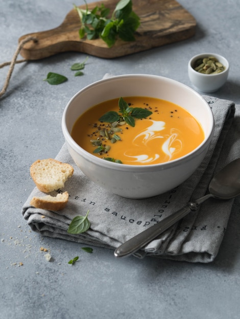 Velouté de potiron dans un bol blanc sur fond gris