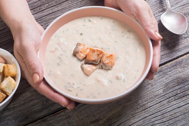 Velouté de saumon et croûtons dans les mains d'une femme