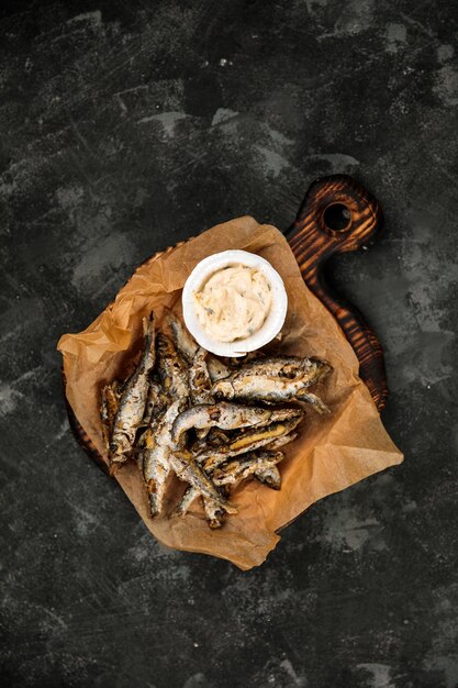 Photo vendace frite avec sauce plat carélien national poisson frit de carélie cuisine du nord de la russie éperlan frit sur un plateau en bois sur fond sombre