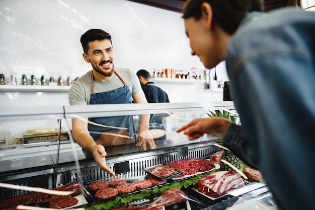 Le vendeur de la boucherie aide à choisir le produit pour une cliente