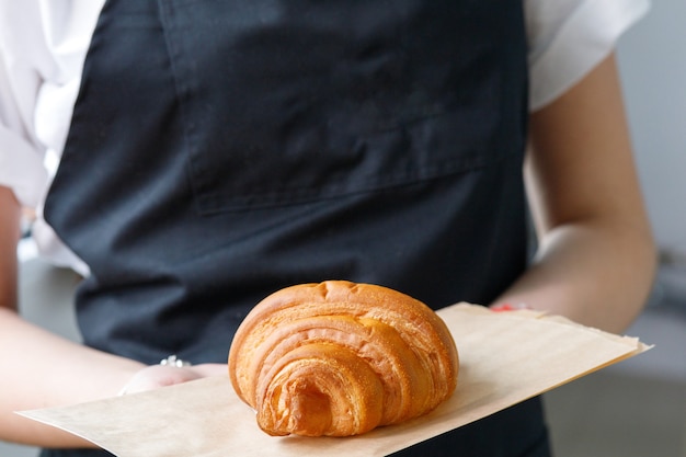 Vendeur de café détient un croissant sur un plateau