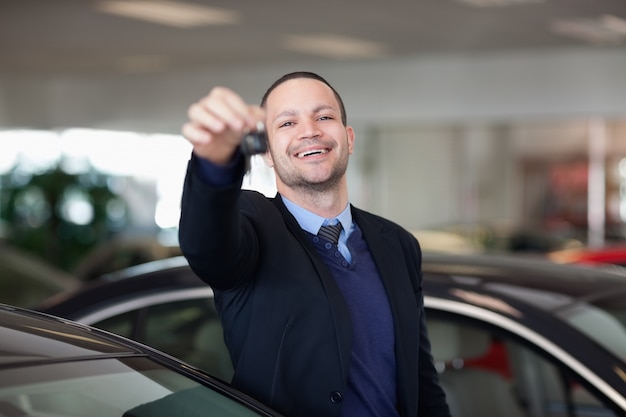 Vendeur debout tout en maintenant les clés de voiture