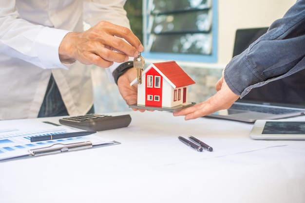 Vendeur donnant la clé de la maison au client dans le concept de financement de prêt d'affaires investissement familial d'assurance loyer