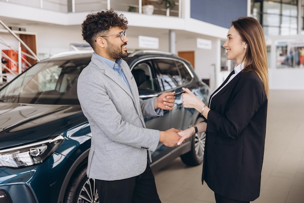 Vendeur donnant la clé de la voiture au client dans un concessionnaire