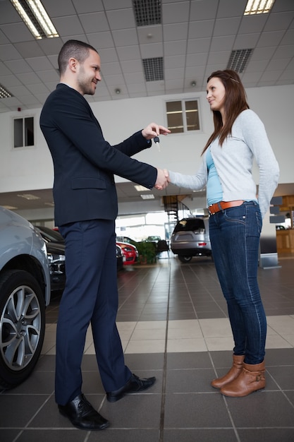 Vendeur donnant des clés de voiture tout en serrant la main d&#39;un client