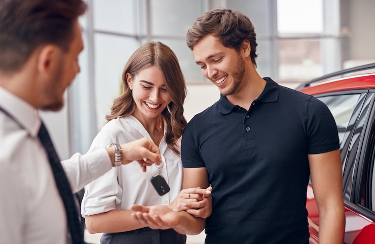 Photo vendeur donnant de nouvelles clés de voiture à un couple heureux