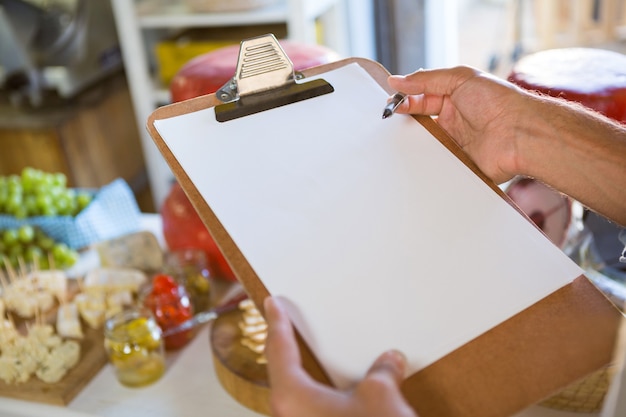 Photo vendeur écrit sur le presse-papiers au comptoir